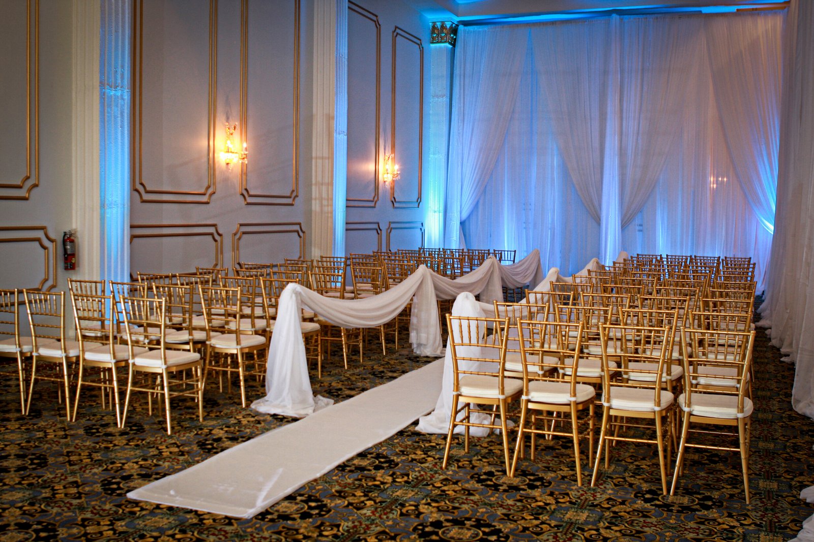 ceremony blue uplighting gold chairs aisle draping