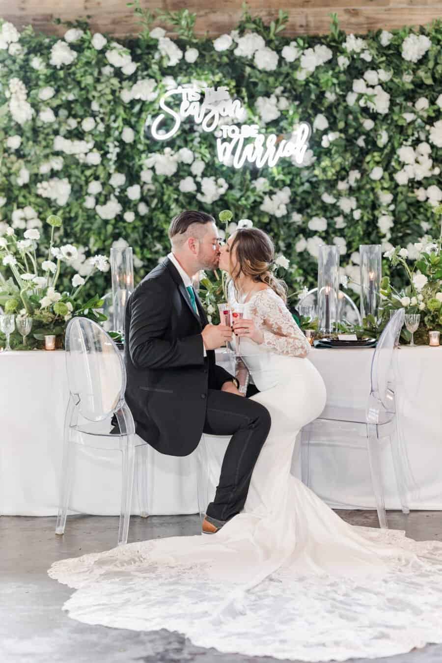 Wedding couple kissing in front of a sign by Tampa event rental business, Gabro Event Services.