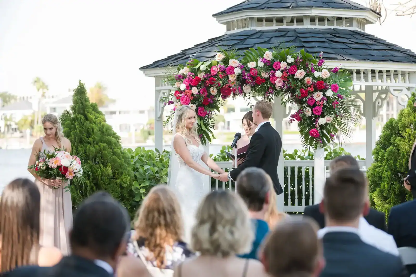 Davis Islands wedding rentals framing Katie and Alex’s vibrant waterfront ceremony beneath a floral arch