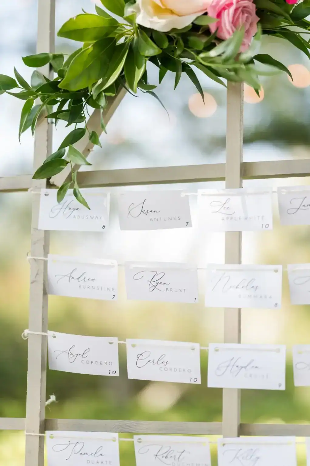 Clothesline-style wedding seating chart displayed with greenery and floral details