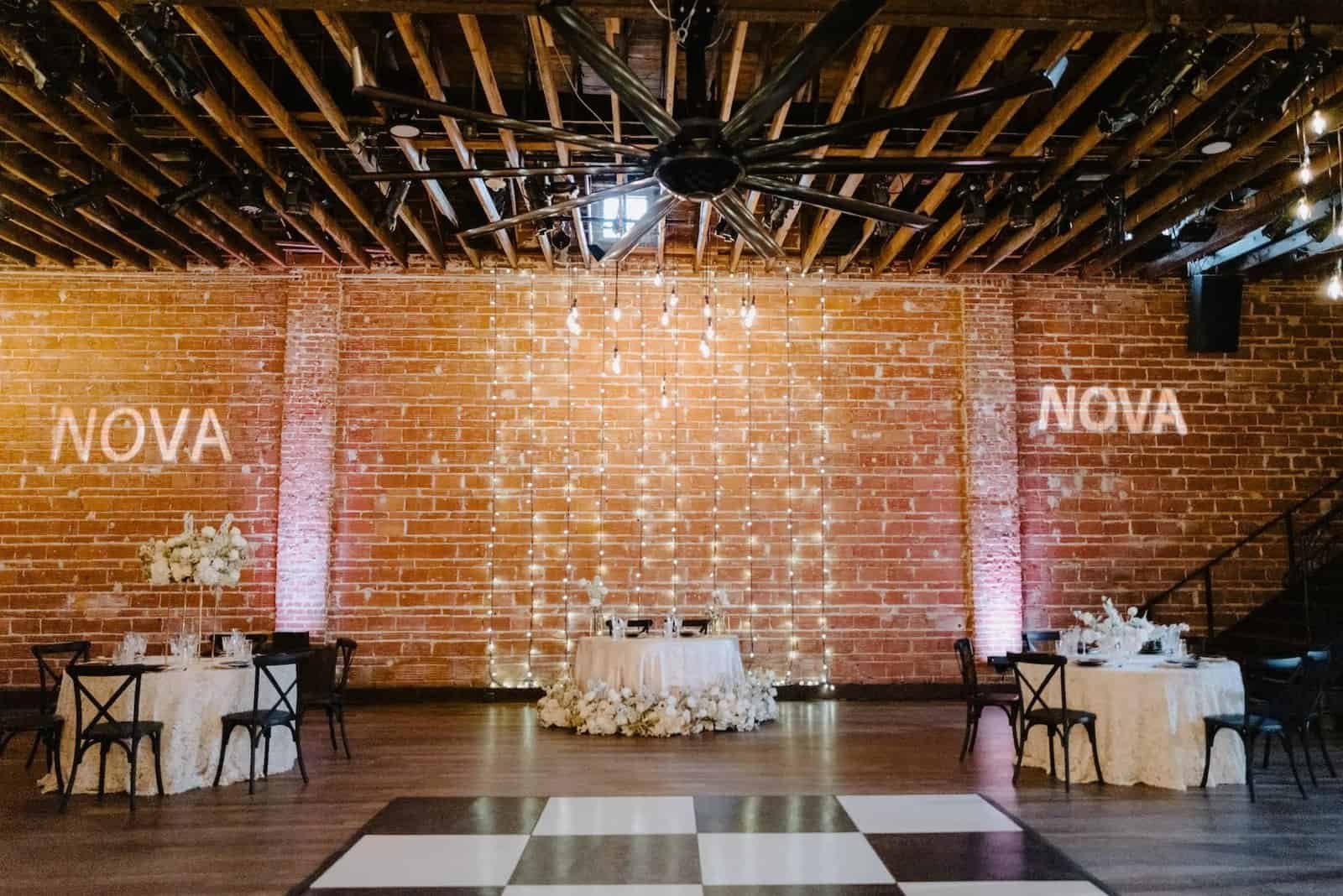 A NOVA 535 reception includes a sweetheart table, guest tables, black chairs, and a checkered dance floor.