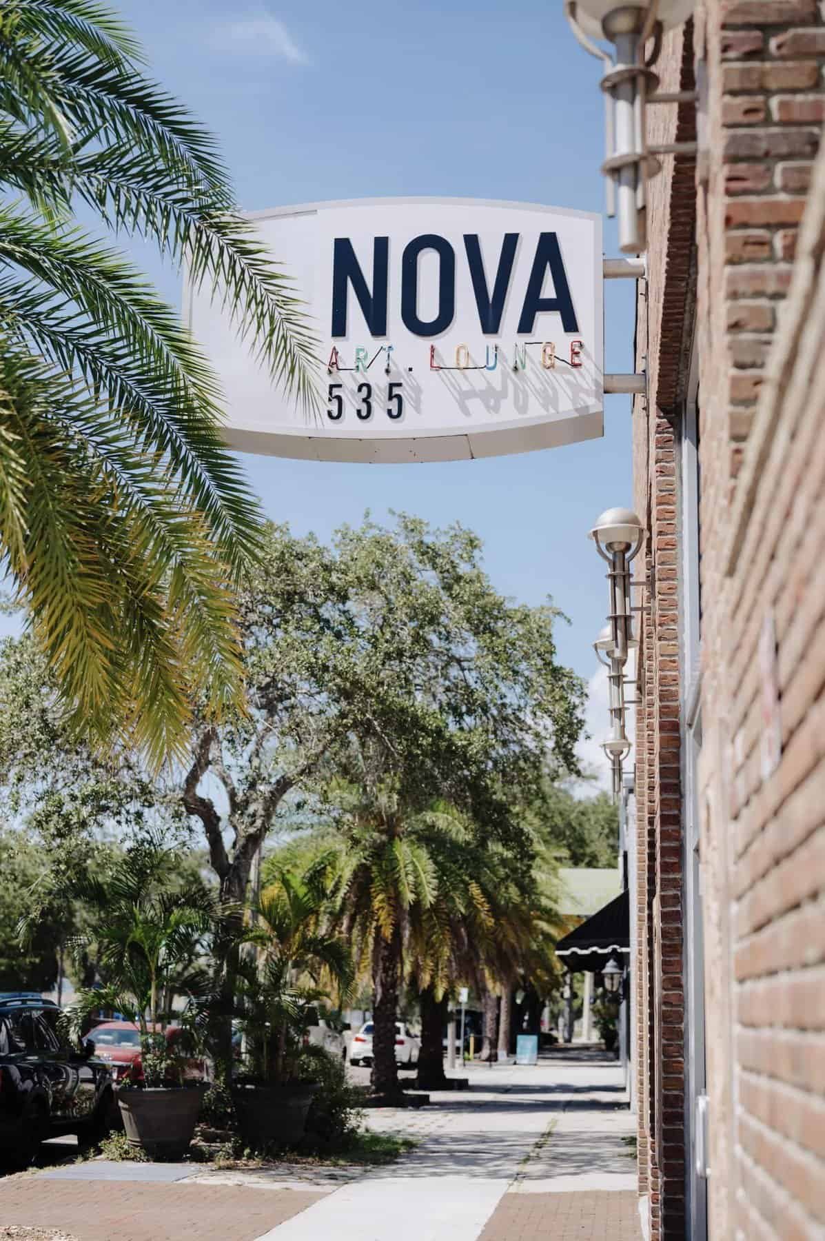 Exterior view of the NOVA 535 venue sign on a brick building with palm trees and a sidewalk.