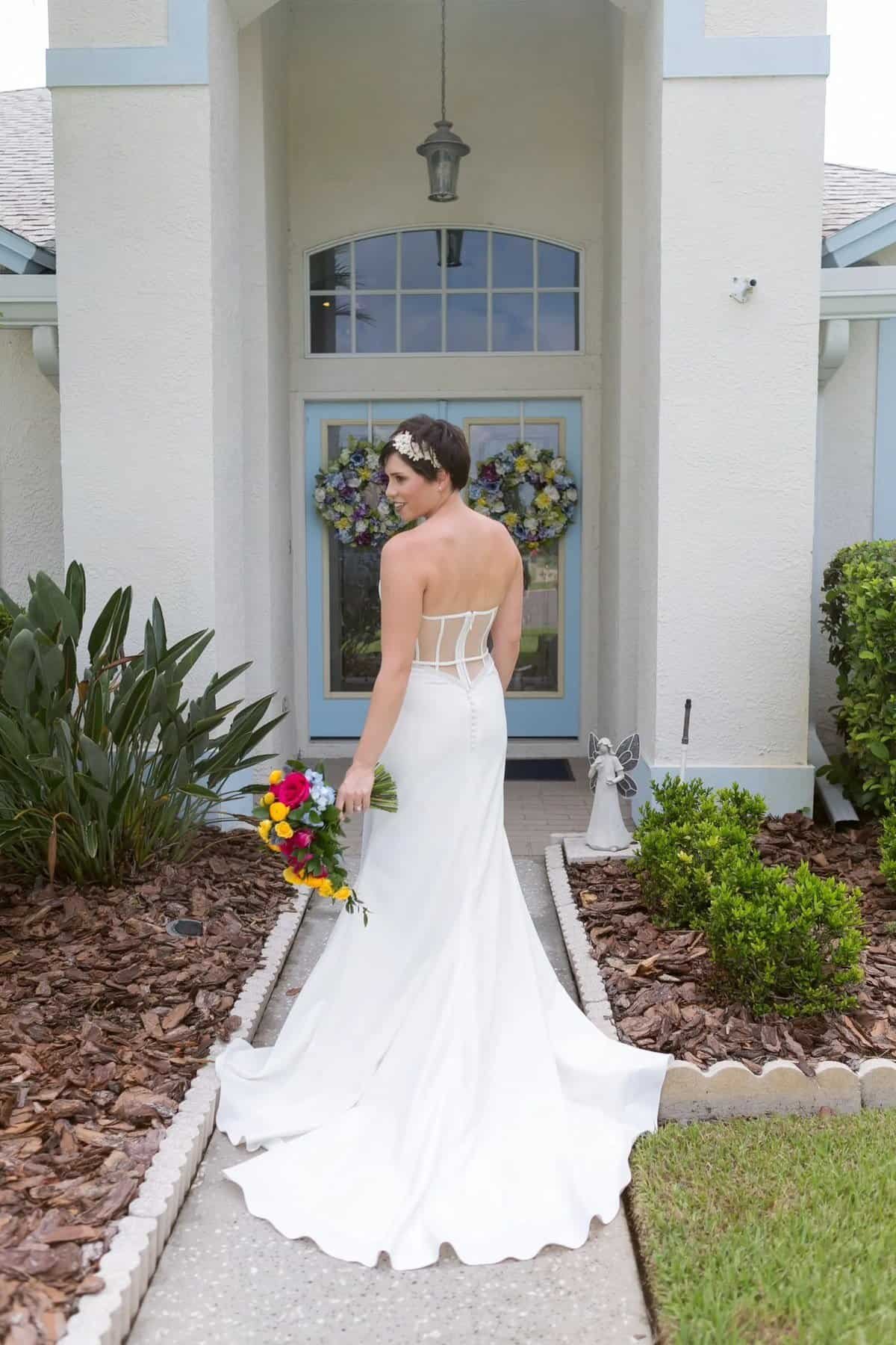 Bride in a white fit-and-flare wedding dress holding a bright bouquet