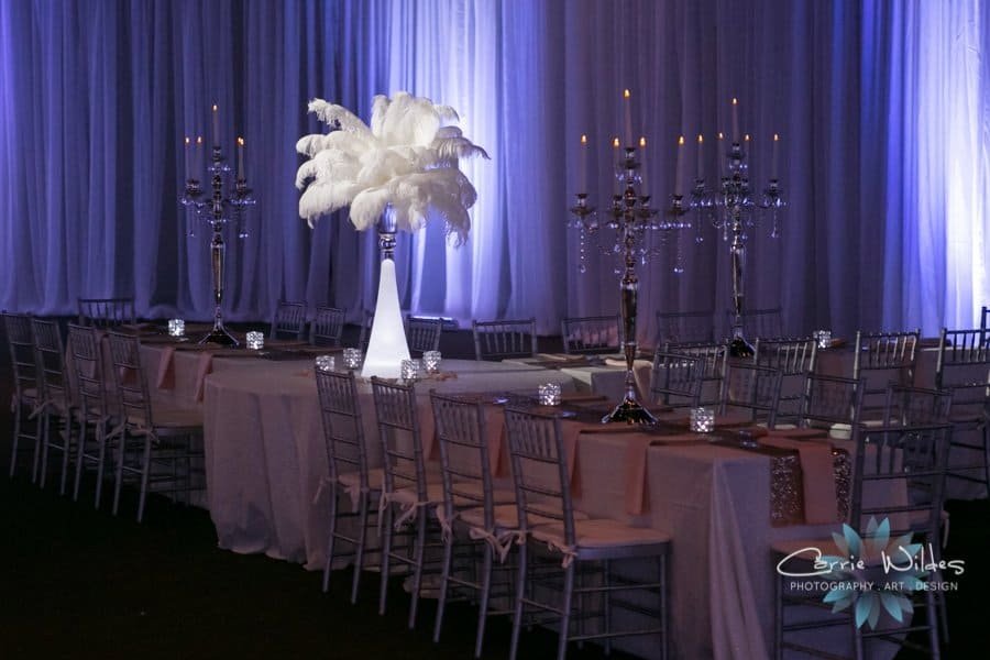 Romantic sweetheart table staged with tailored ivory linens and sheer cascading fabric wall draping