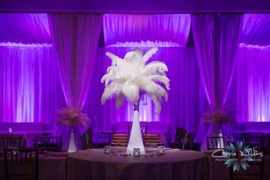 Towering multi-tier wedding cake highlighted with precision theatrical lighting against a draped fabric backdrop