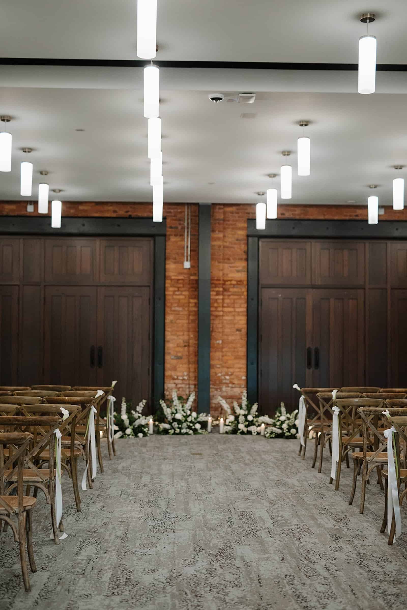 Long reception tables featuring black linens, white floral bud vases, and warm candlelight.