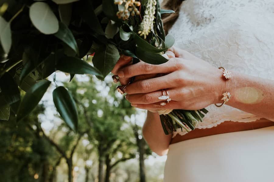 Newlyweds holding hands and strolling through the natural landscape of Casa Lantana during golden hour sunset