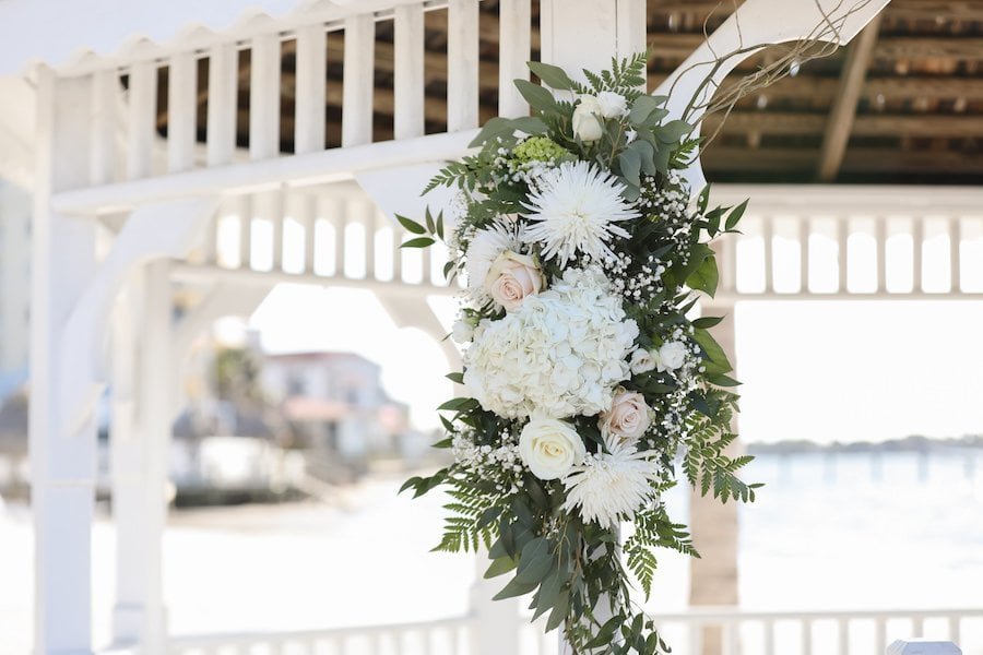 Outdoor wedding ceremony arch decorated with lush pink roses, ferns, and eucalyptus at Countryside Country Club