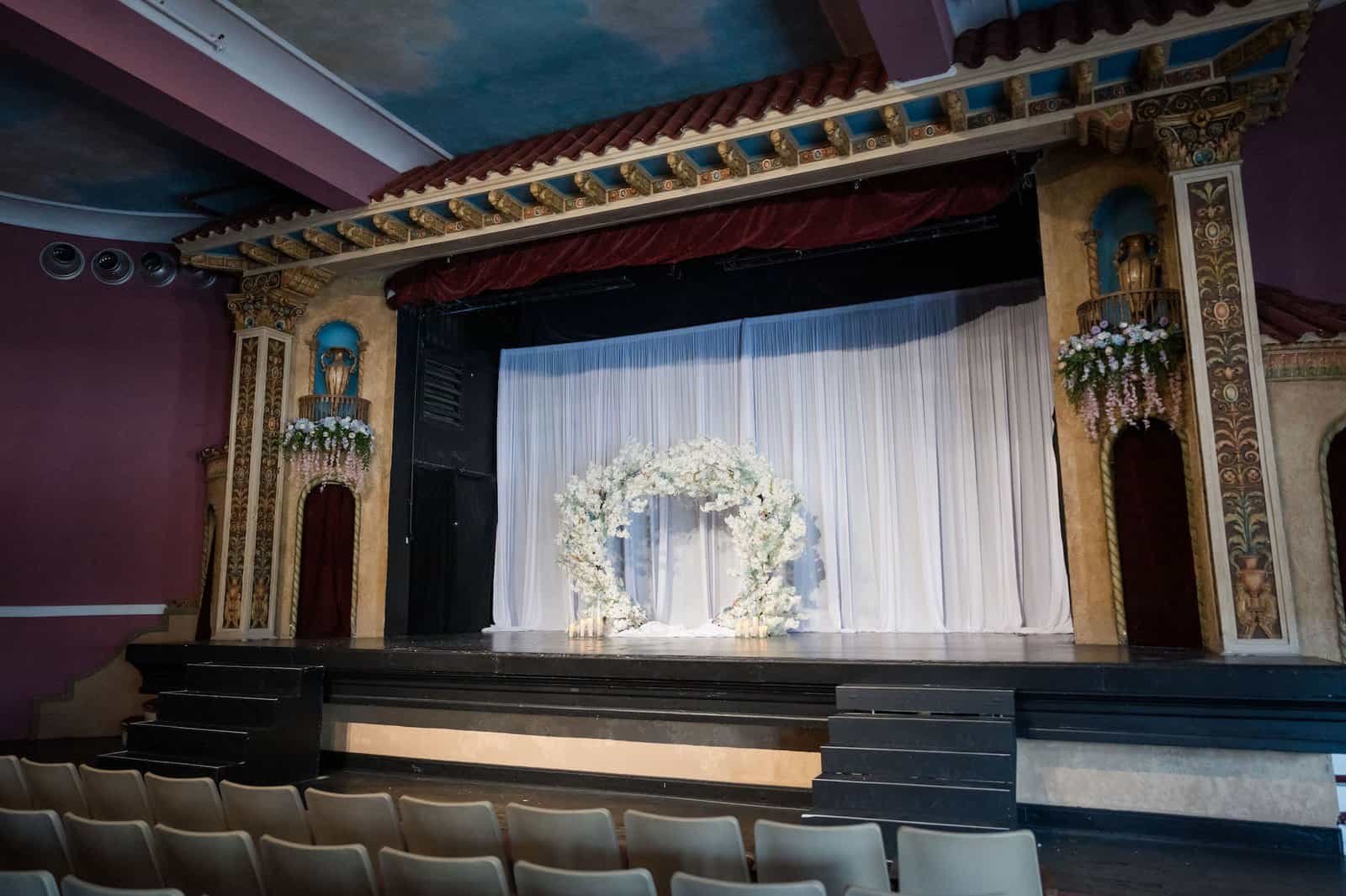 Historic theater stage ceremony setup with circular flower arch at The Cuban Club
