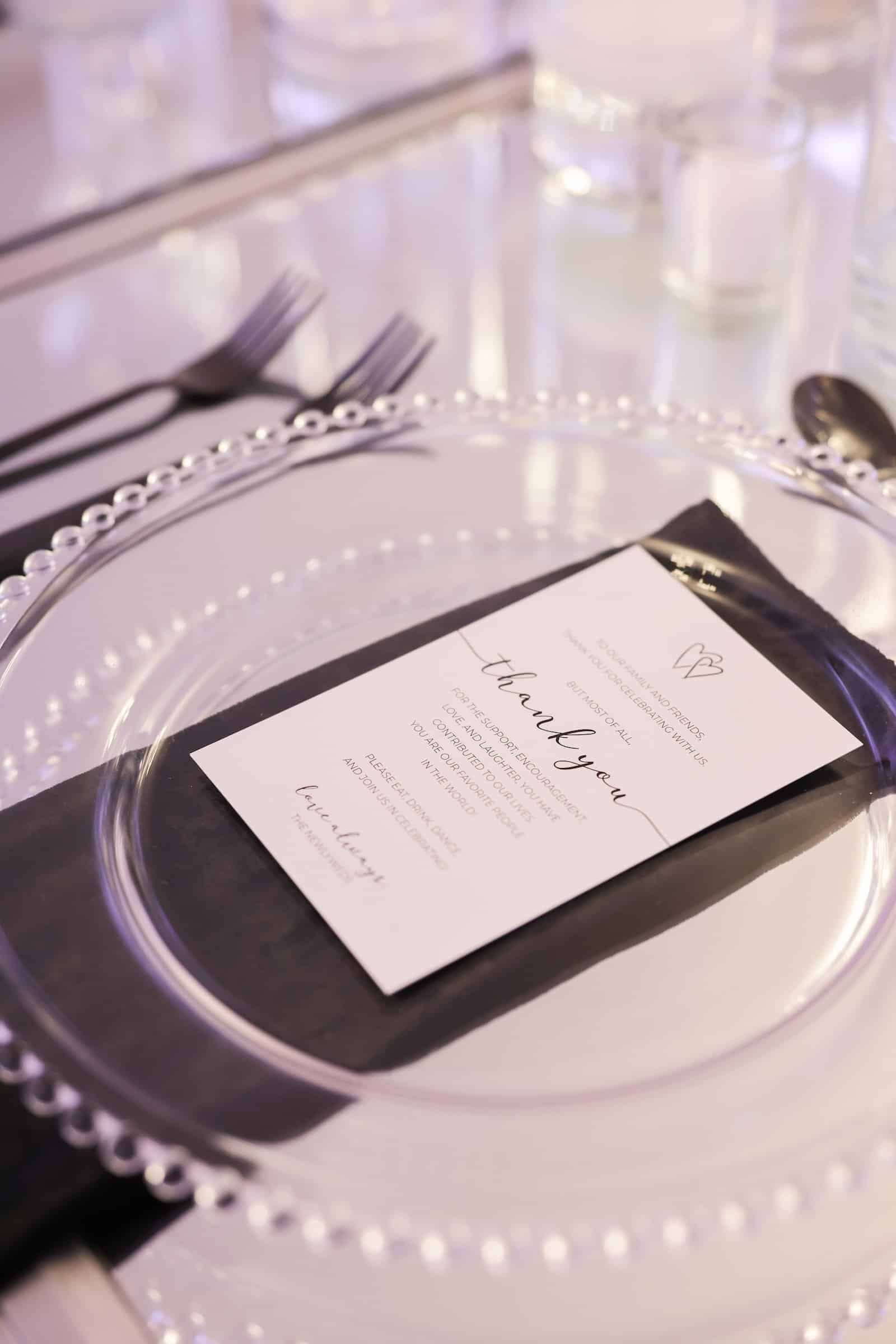 Place setting with a beaded clear charger, black flatware and a black-bordered menu card