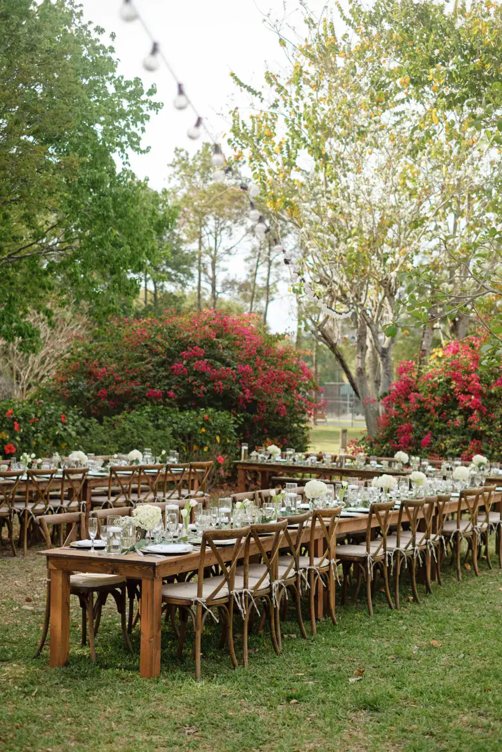 Long wood farm tables set on the lawn among bougainvillea at Davis Island Garden Club
