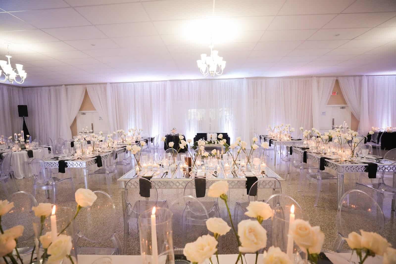 Reception at Davis Island Garden Club with white draped walls, clear acrylic chairs, black napkins and candlelit tables