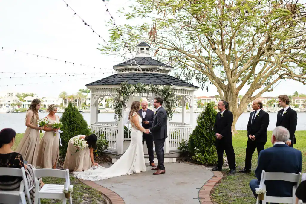 Open-air reception dining tables glowing under canopy of warm bistro lights for Tampa waterfront wedding
