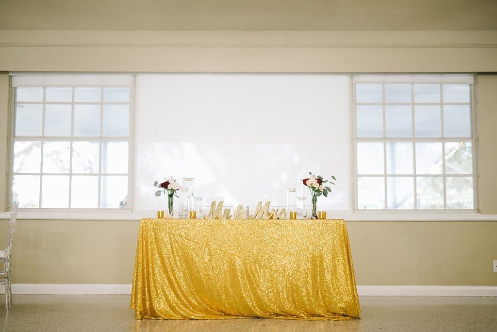 Intimate sweetheart table at The Don CeSar framed by elegant white draping, tall floral columns, and warm uplighting