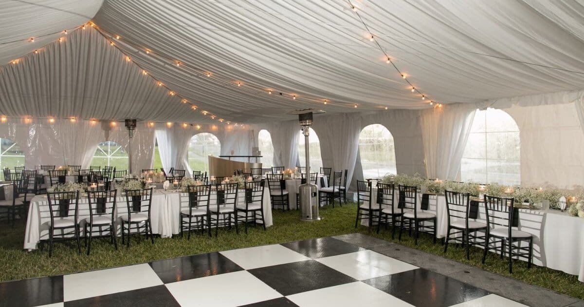 White pleated tent draping and bistro string lighting above a black and white checkered dance floor at The Fenway
