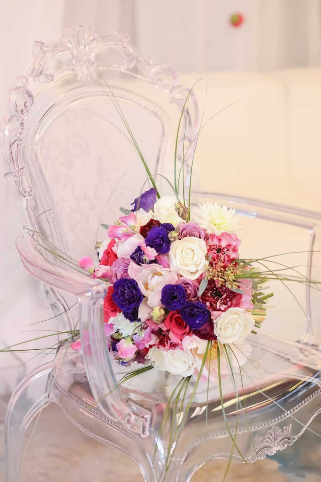 Modern clear acrylic Victorian armchair styled with fresh bridal bouquet at Gabro Event Services showroom