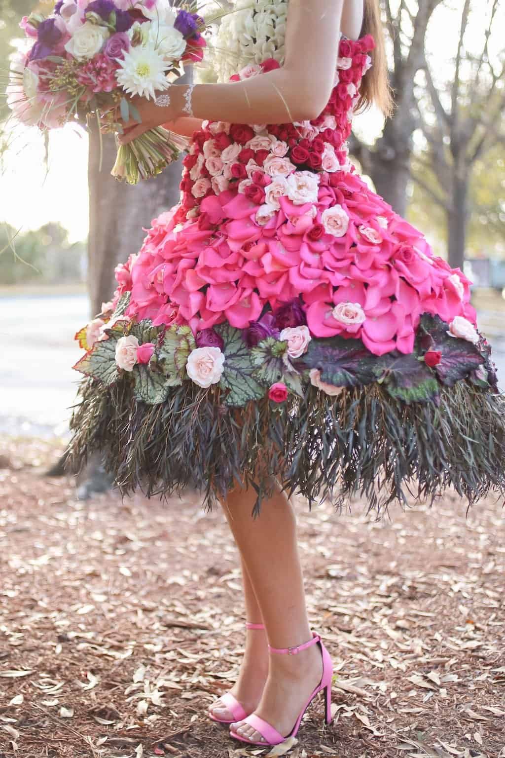 Editorial portrait of living floral gown featuring fresh pink roses, white blooms, and greenery accents