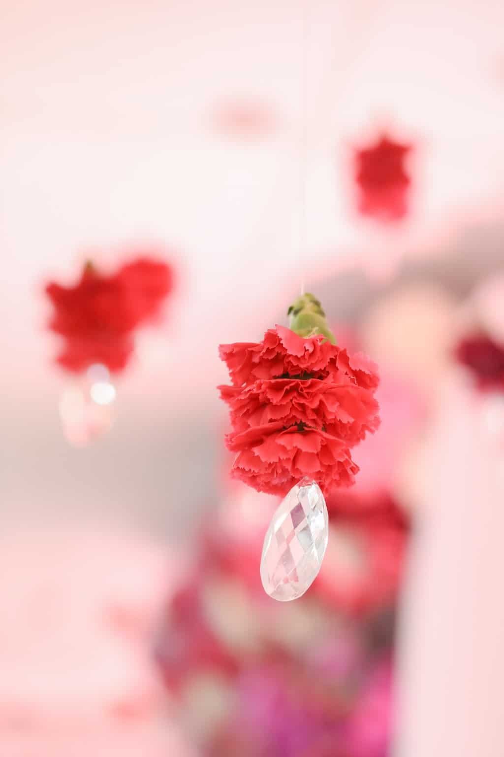 Close-up detail of hanging suspended pink carnations and shimmering crystal beads floral ceiling installation