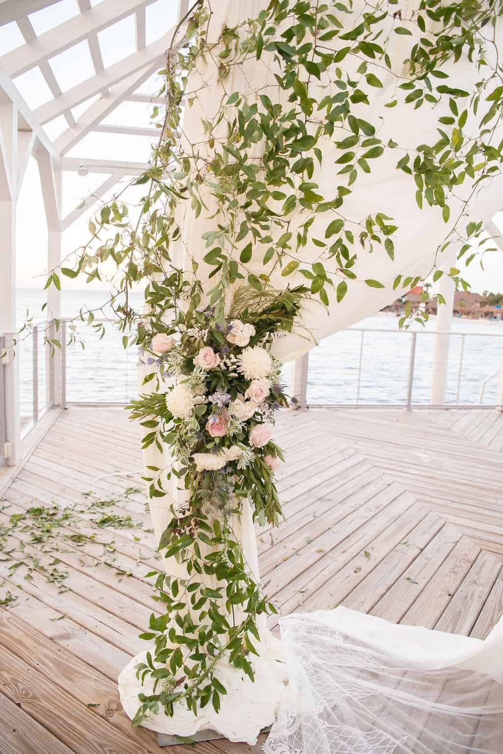 Waterfront wedding ceremony canopy with custom sheer white fabric draping and blush floral accents at The Godfrey