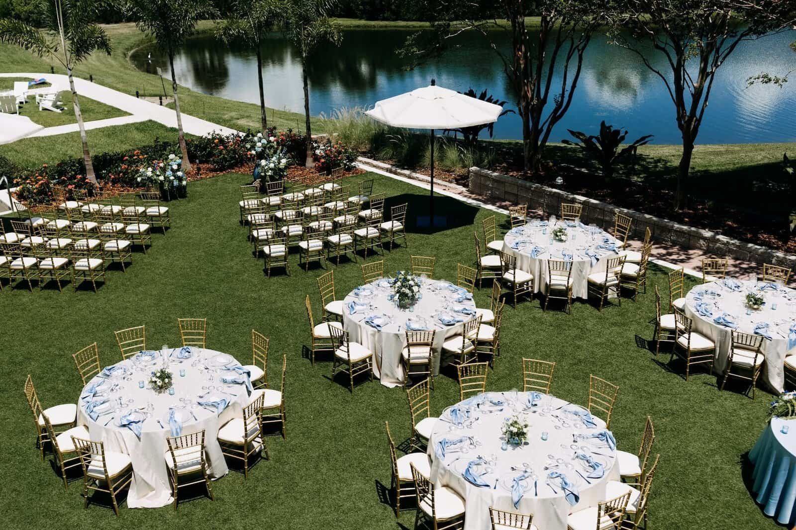Round reception tables with blue and white linens and gold chairs set on the lawn at Grand Hyatt Tampa Bay