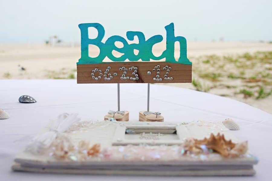 A large white reception tent glowing at dusk on the Clearwater sand.