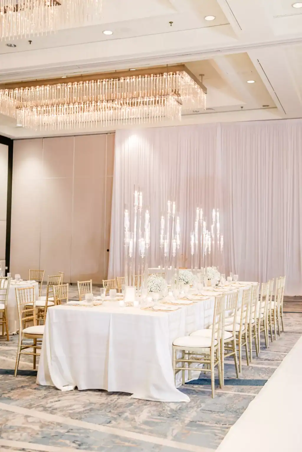 Blush uplighting washing full-height white draping in the Hilton Tampa Downtown ballroom