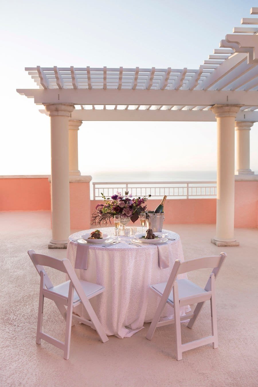 Intimate dinner tablescape inside the Caladesi Room with sheer ivory wall draping, market string lighting, and ocean blue linens
