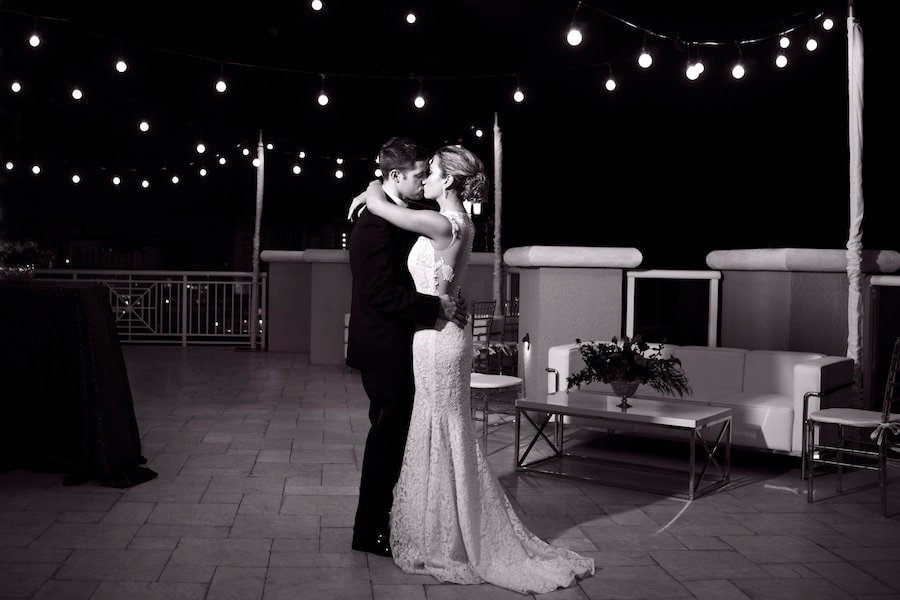 Bride and groom sharing romantic first dance under warm bistro string lights and flowing wall draping in the Caladesi Room