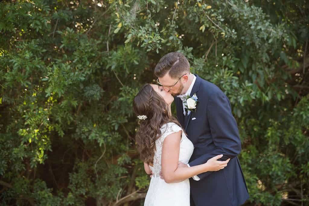 A beautiful wooden ceremony arch by Gabro Event Services under mossy oak trees.