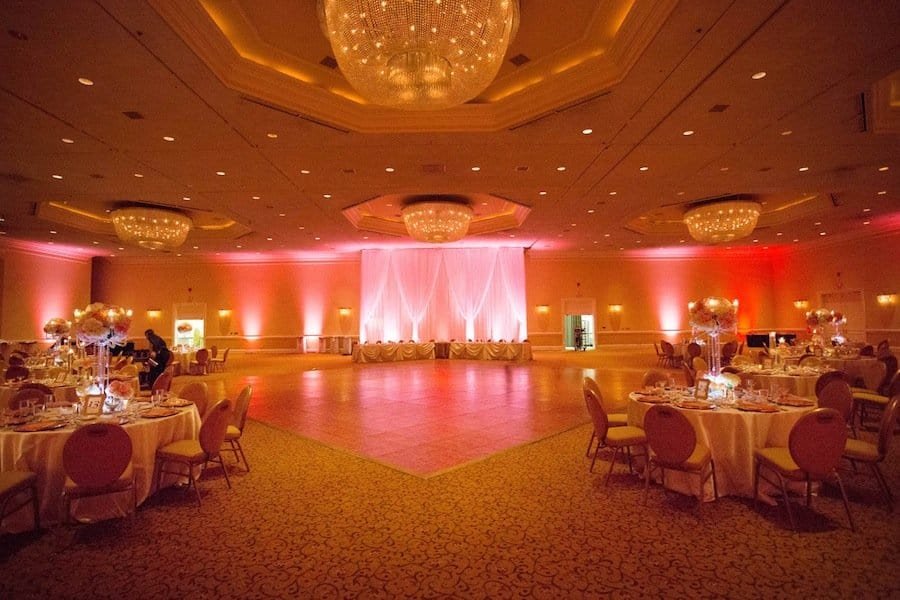 Grand wedding reception ballroom at Innisbrook Resort decorated with gold Chiavari chairs, crystal chandeliers, and coral floral centerpieces
