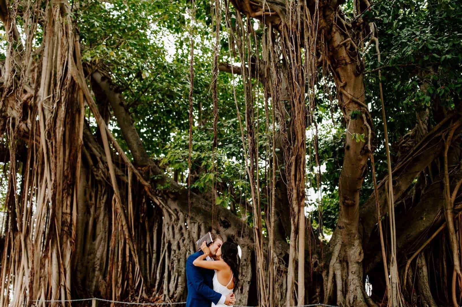 The bride and groom sharing a romantic moment amidst tropical foliage and orchids.