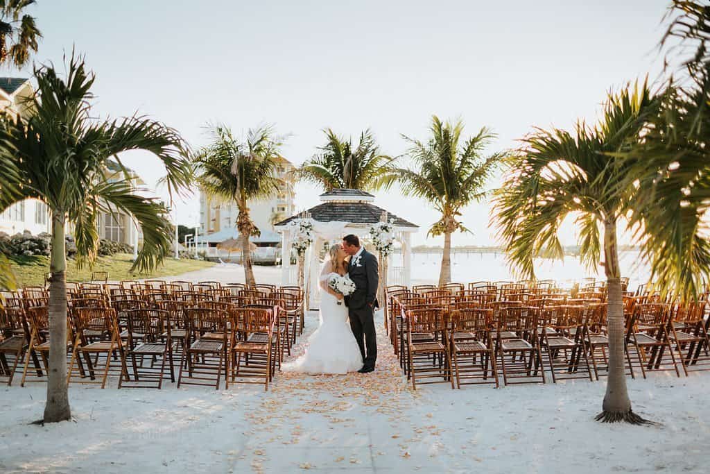 Outdoor wedding ceremony at Isla Del Sol waterfront gazebo with birchwood arch and sheer white fabric draping