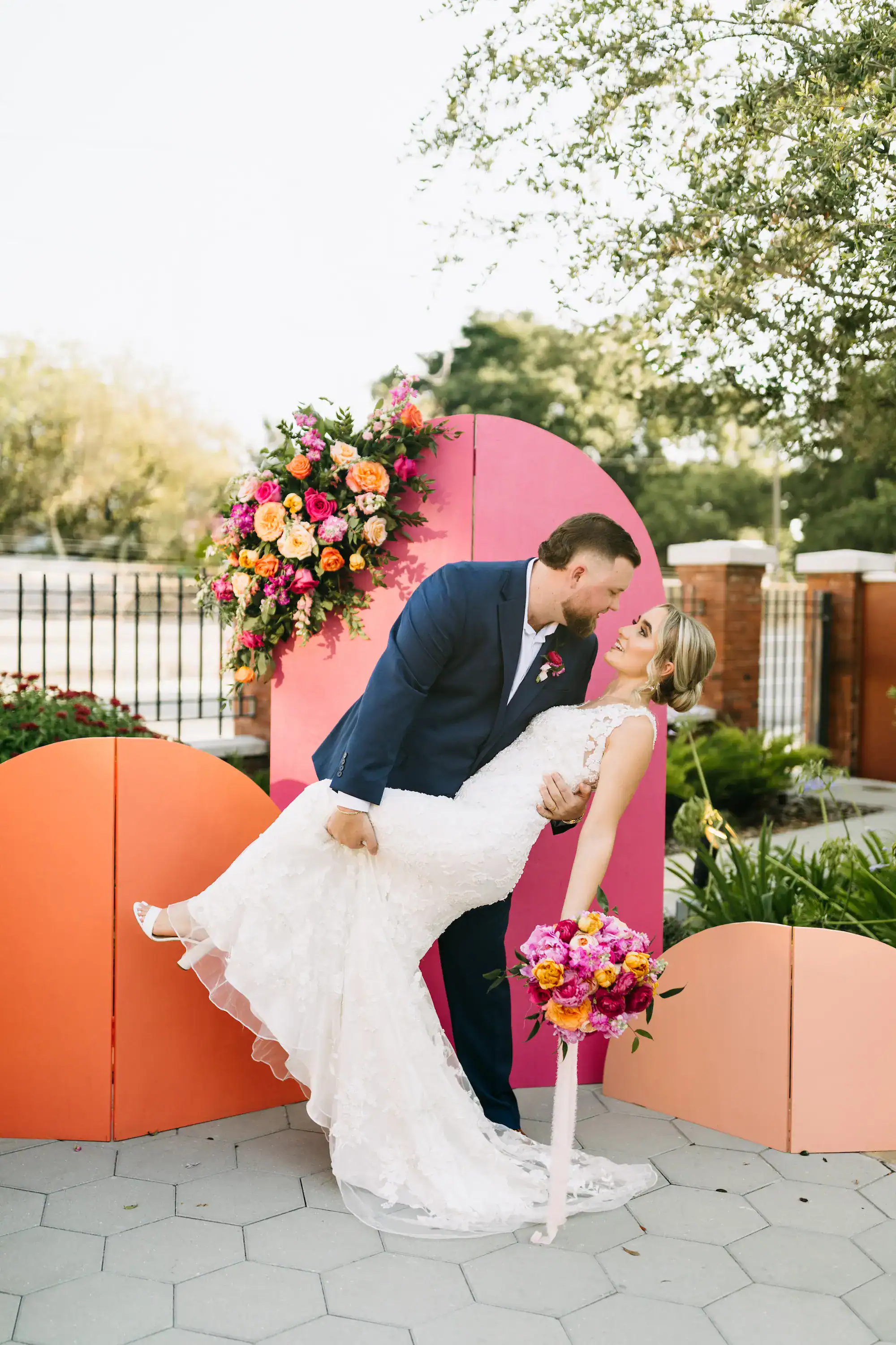 A bride in a lace gown posing in a sun-drenched historic park.