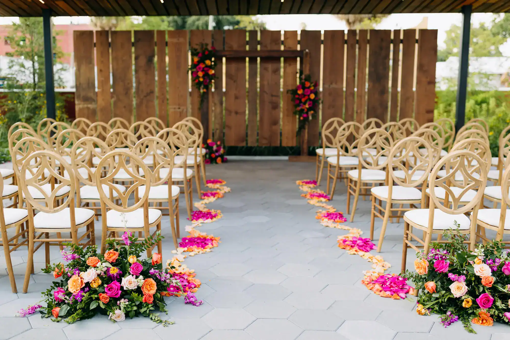 Vibrant pink and orange rustic outdoor wedding ceremony rose petal aisle with wooden arch