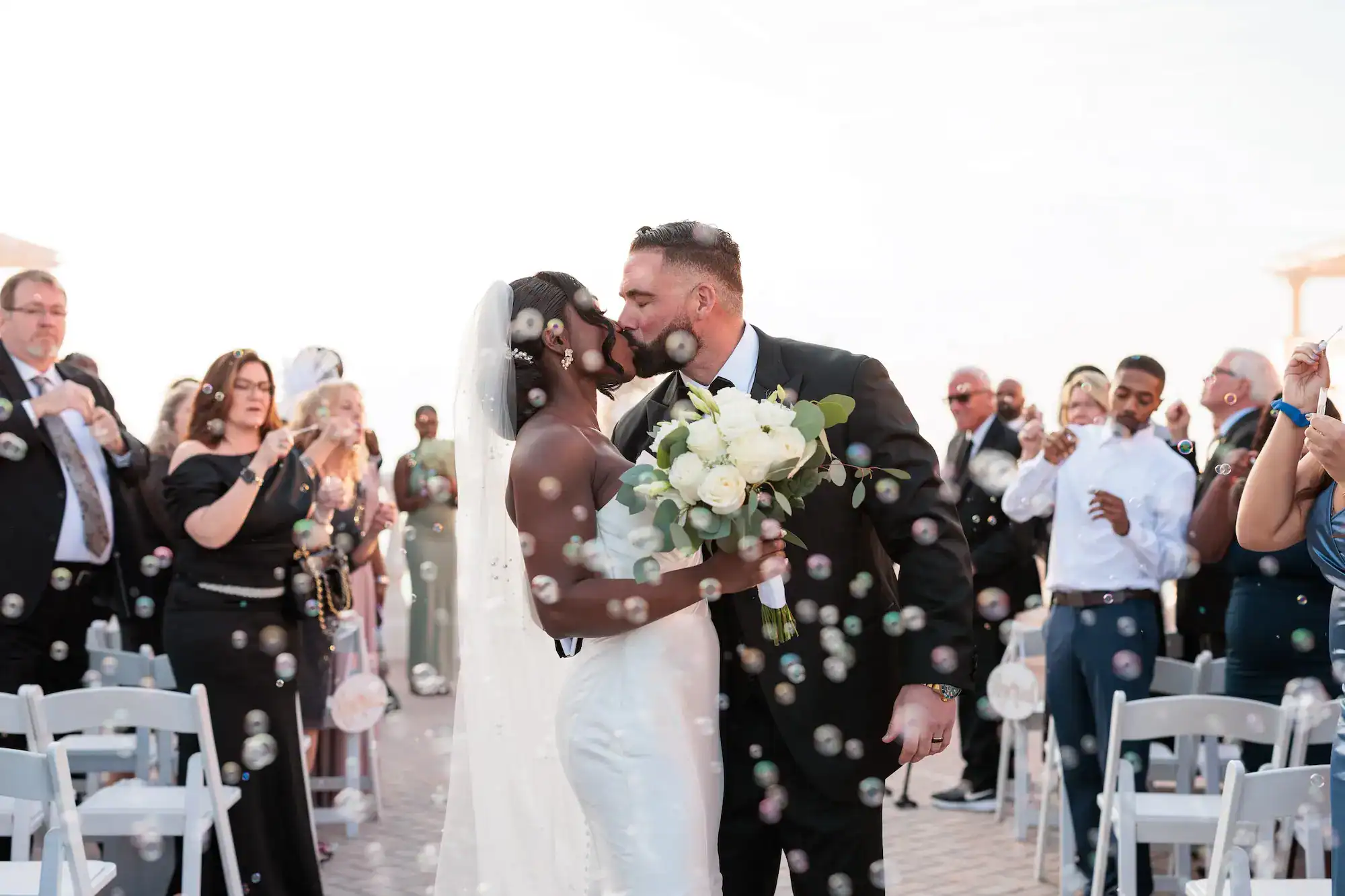A stunning ballroom reception featuring lush greenery arrangements and elegant white and gold table settings.