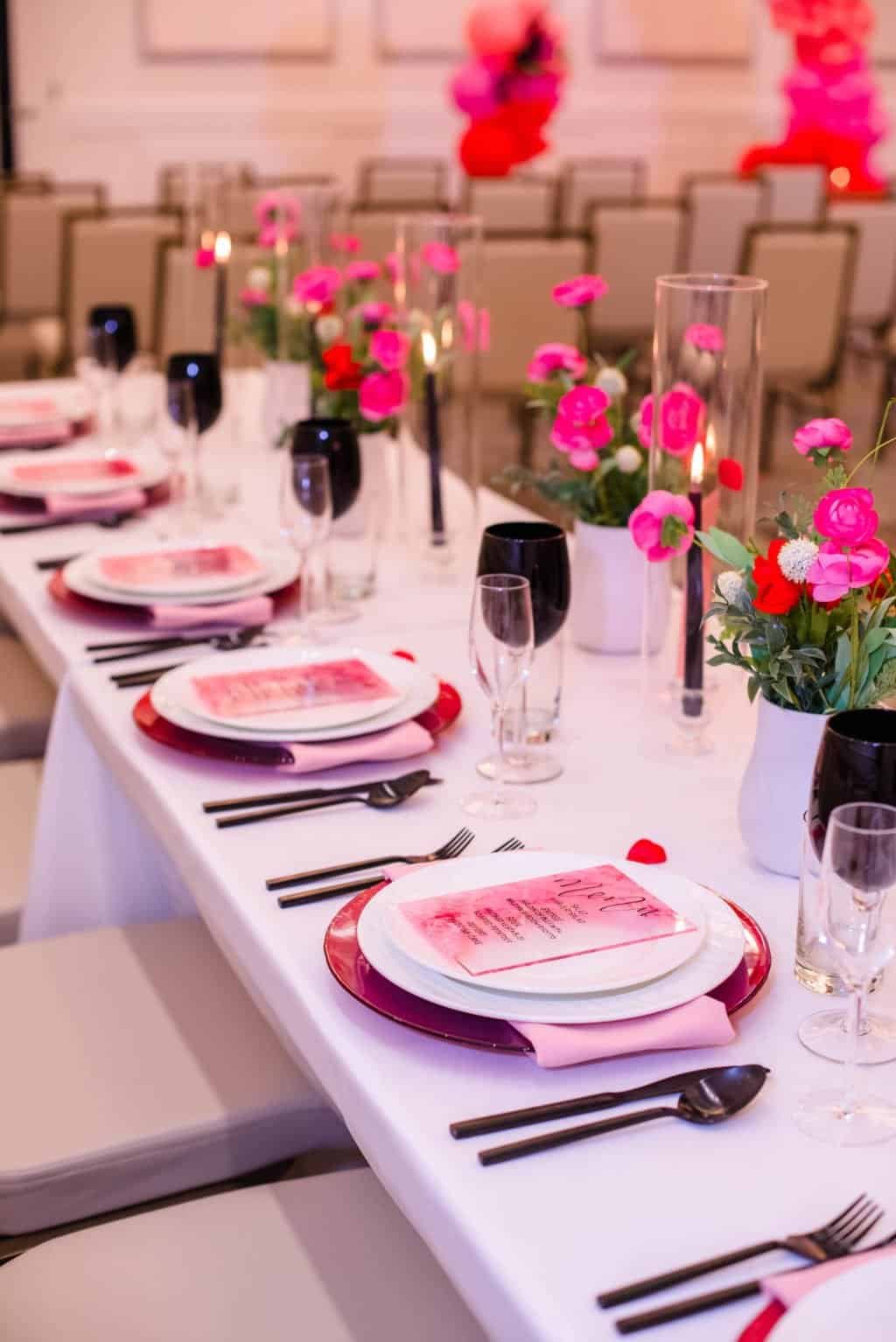 Contemporary Valentine feasting table with red hurricane taper candles and lush rose runner at The Karol Hotel