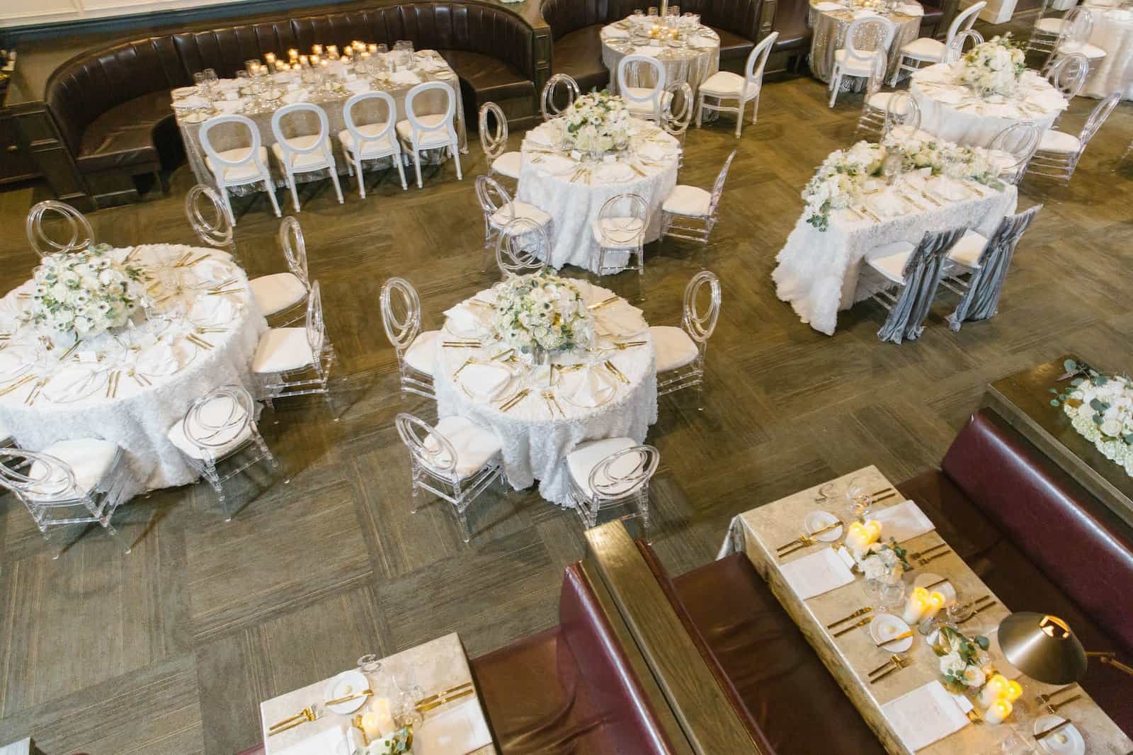 Luxurious ballroom dining layout with tall white centerpieces, gold accents, and warm ambient illumination