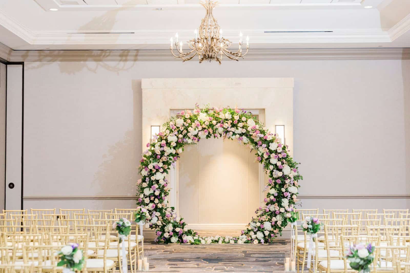 Grand circular ceremony floral arch with gold chiavari chairs in Tampa Marriott Water Street ballroom