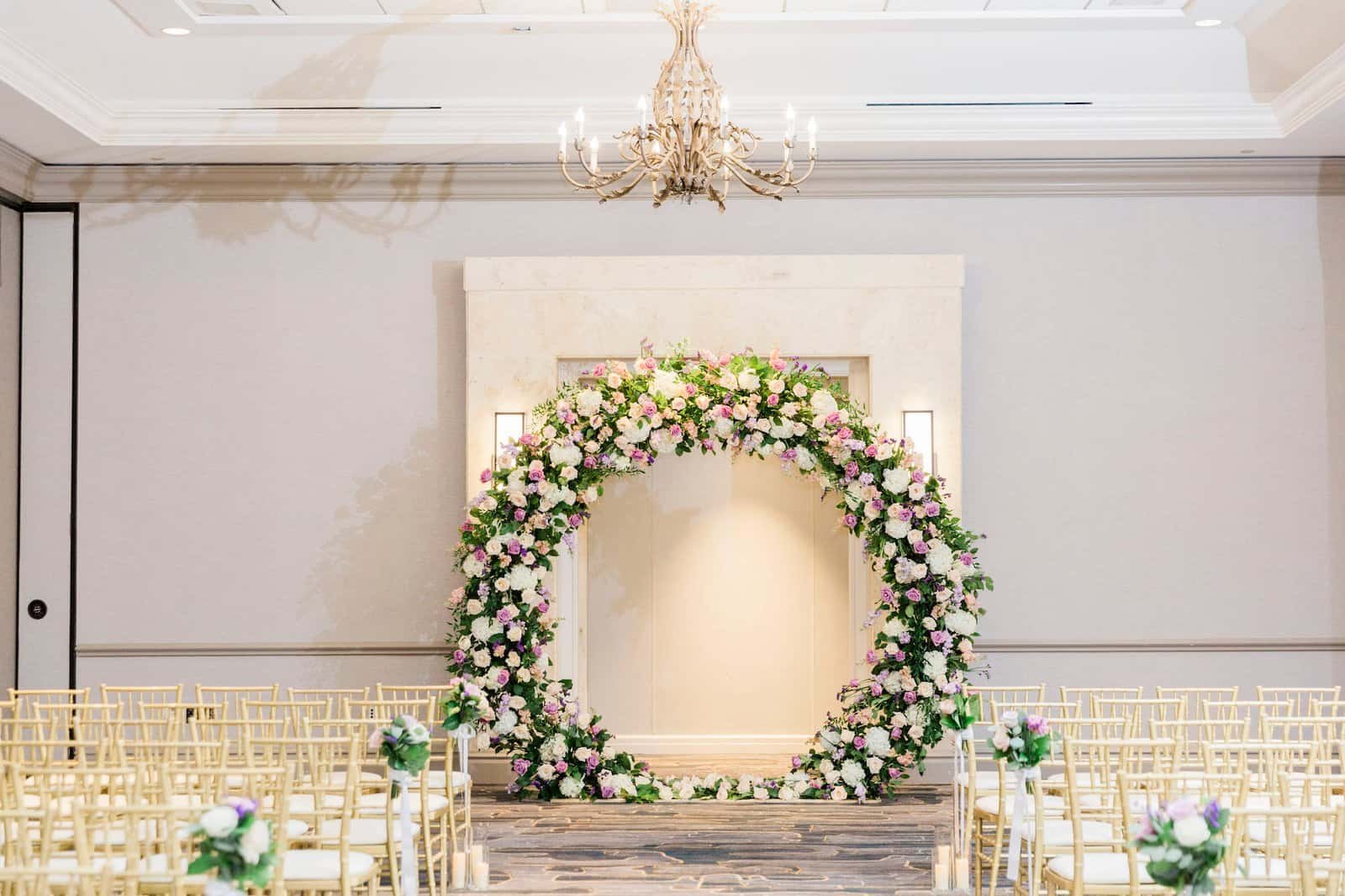 Grand circular ceremony floral arch with gold chiavari chairs in Tampa Marriott Water Street ballroom