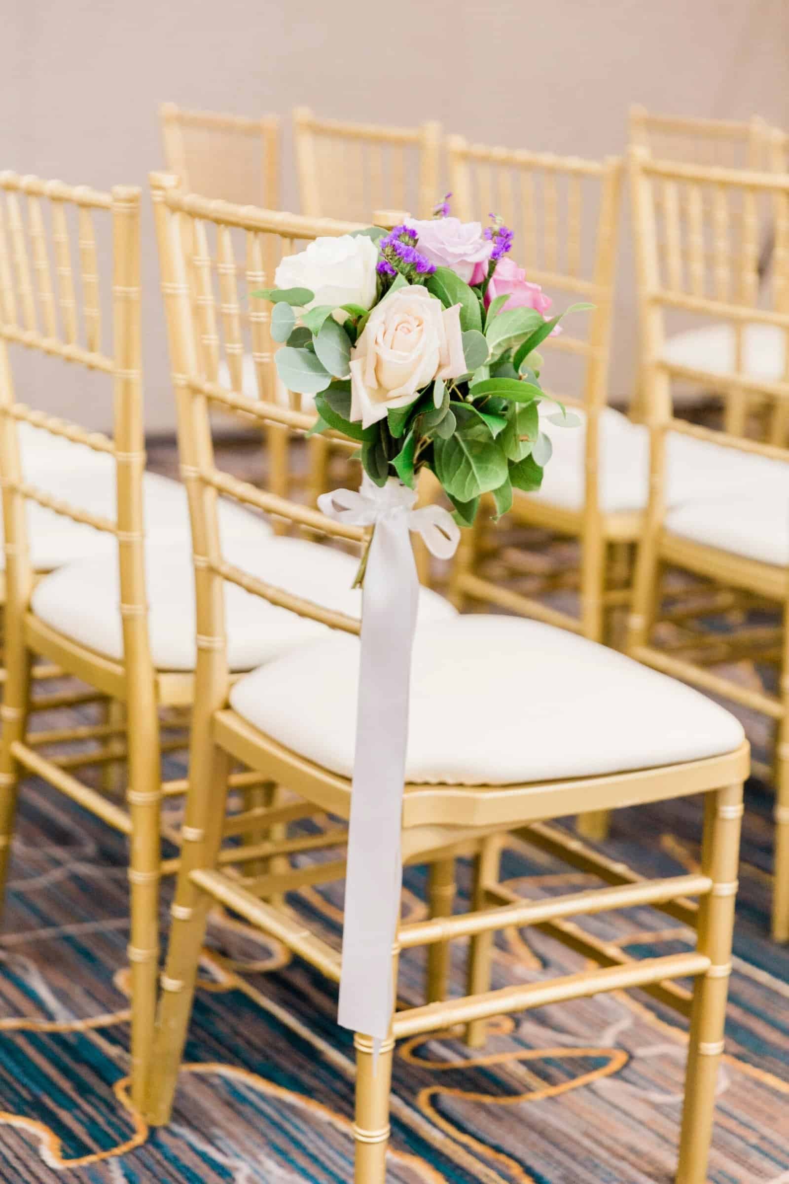 Ceremony aisle lined with lavender, blush, and ivory floral arrangements and gold chiavari chairs