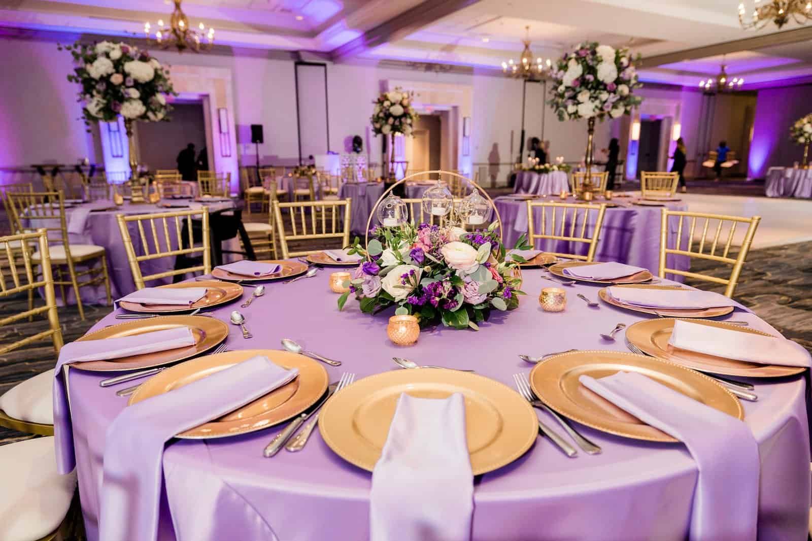 Metallic gold charger plates layered over lavender satin tablecloths with custom menu cards