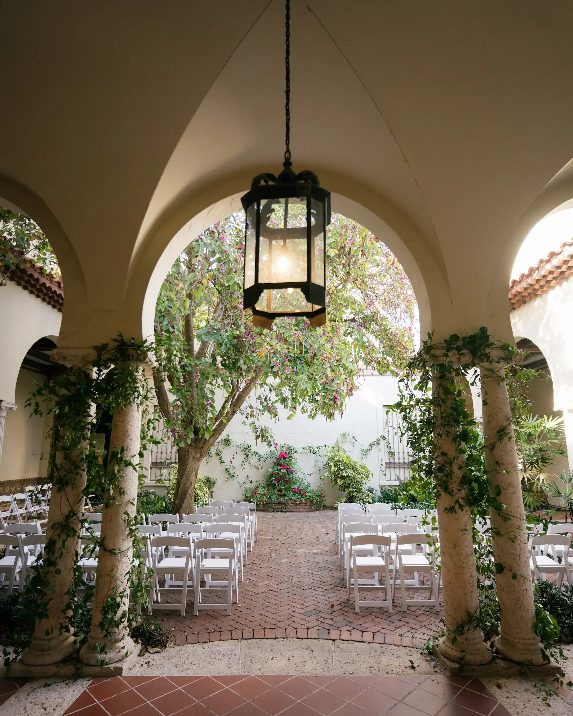 Vibrant tropical ceremony floral arch with pink garden roses, anthuriums, and monstera leaves