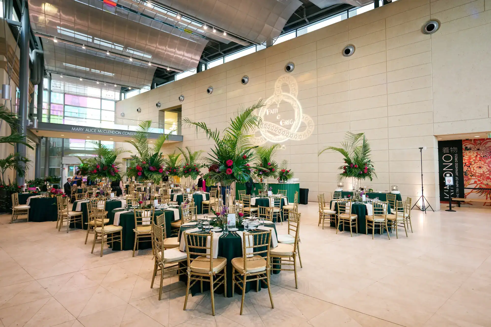 Museum conservatory lounge featuring emerald green velvet sofas, gold accent tables, and decorative bar by Gabro Event Services