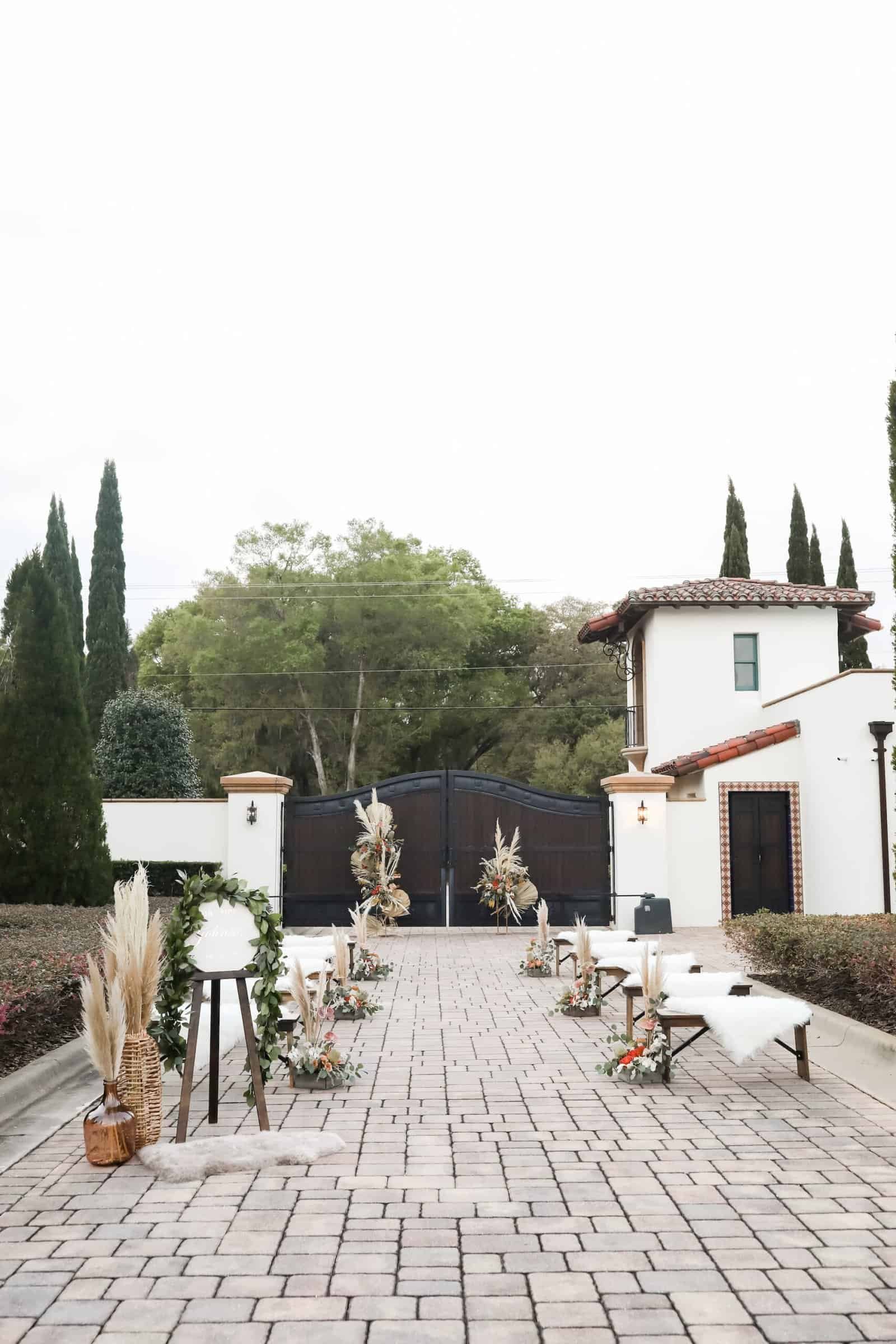 Outdoor boho lakeside ceremony setup with wooden benches and dried floral half arch at Mision Lago Estate