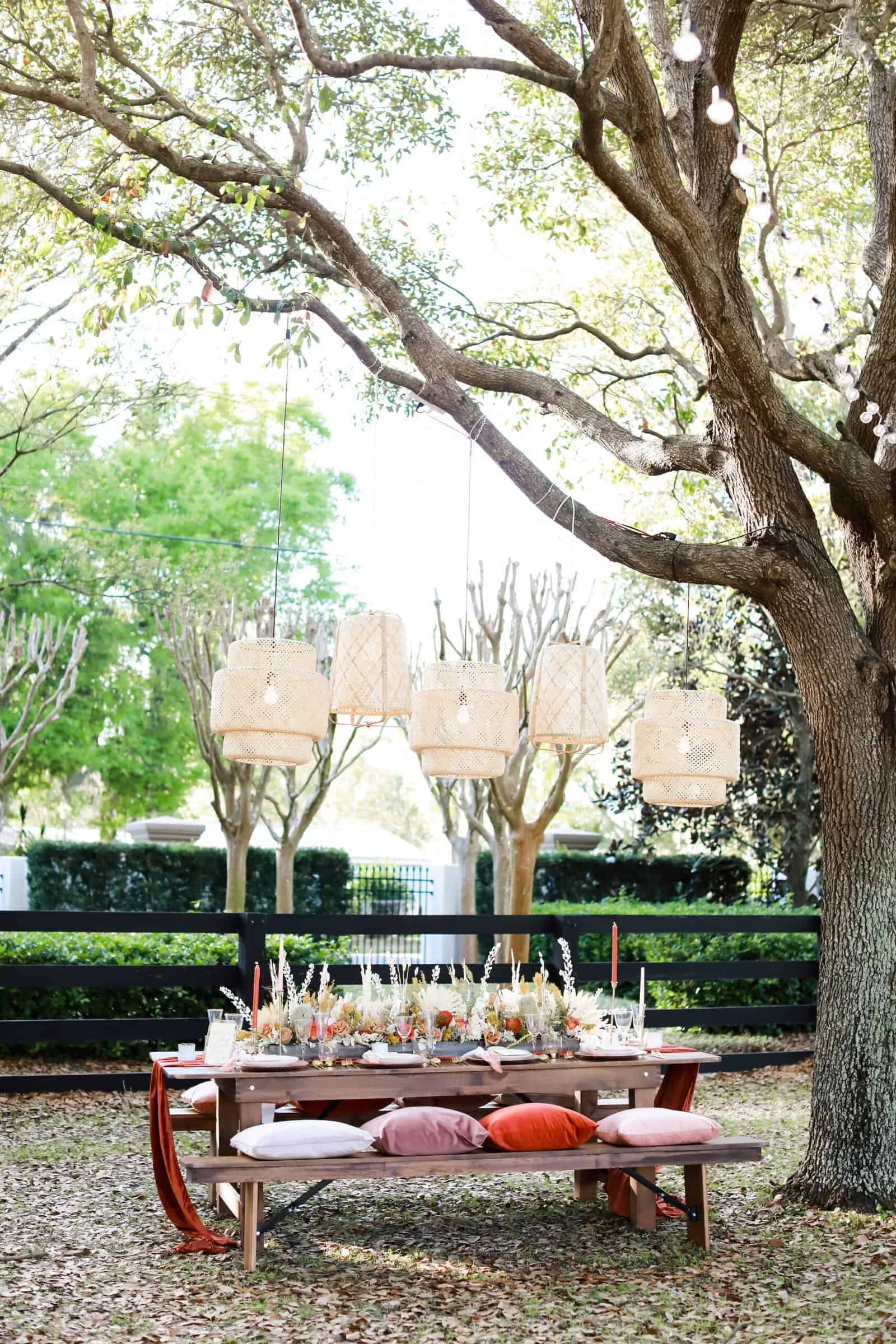 Rustic wooden farm feasting table and bench reception setup on lakeside lawn by Gabro Event Services