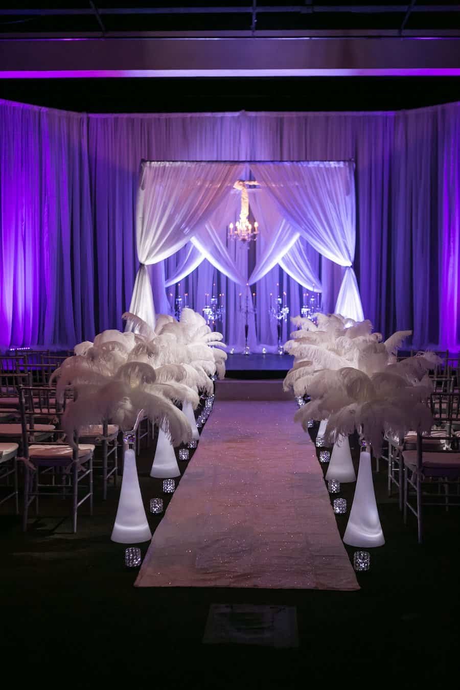 All-white ceremony sanctuary with sweeping ceiling draping canopy and silver Chiavari chairs by Gabro Event Services
