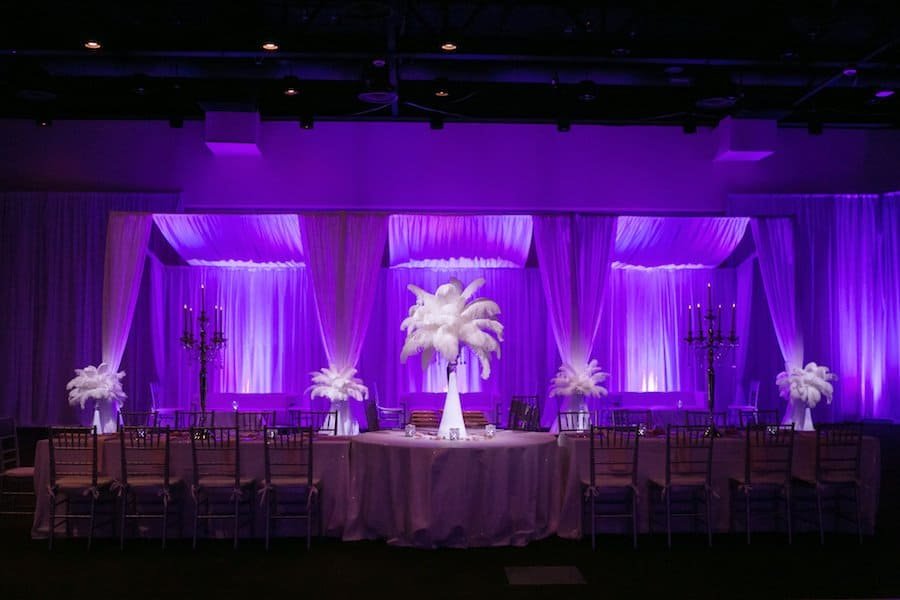 Complete ballroom transformation with floor-to-ceiling white wall drapery and dynamic architectural uplighting by Gabro Event Services