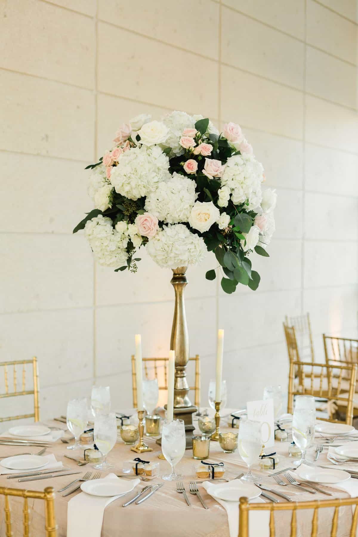 Elegant museum reception dining tables framed by gold Chiavari ballroom chairs and lush white hydrangea centerpieces