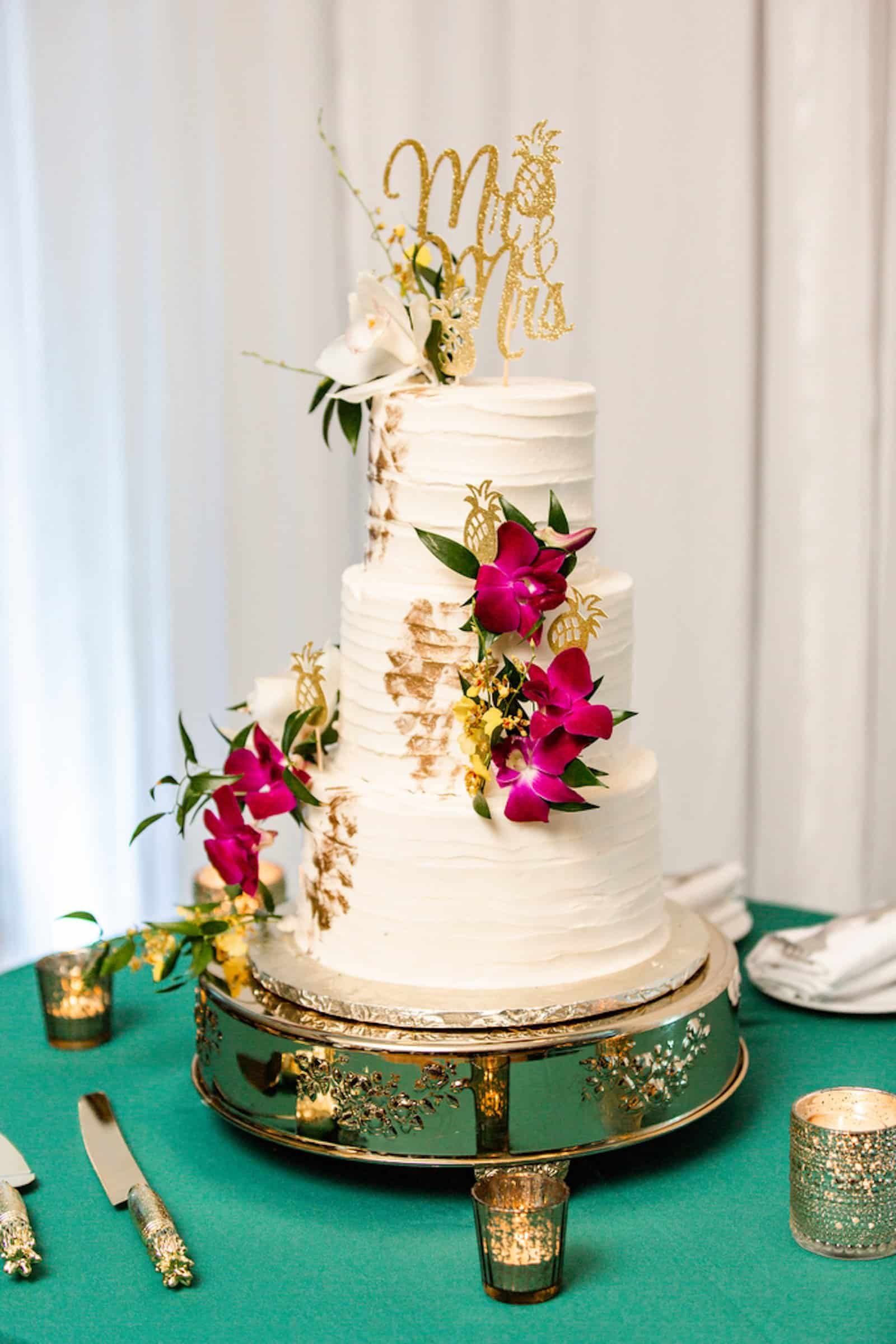 Three Tier Elegant White Wedding Cake by A Piece of Cake with Purple Orchids and Gold Cake Topper