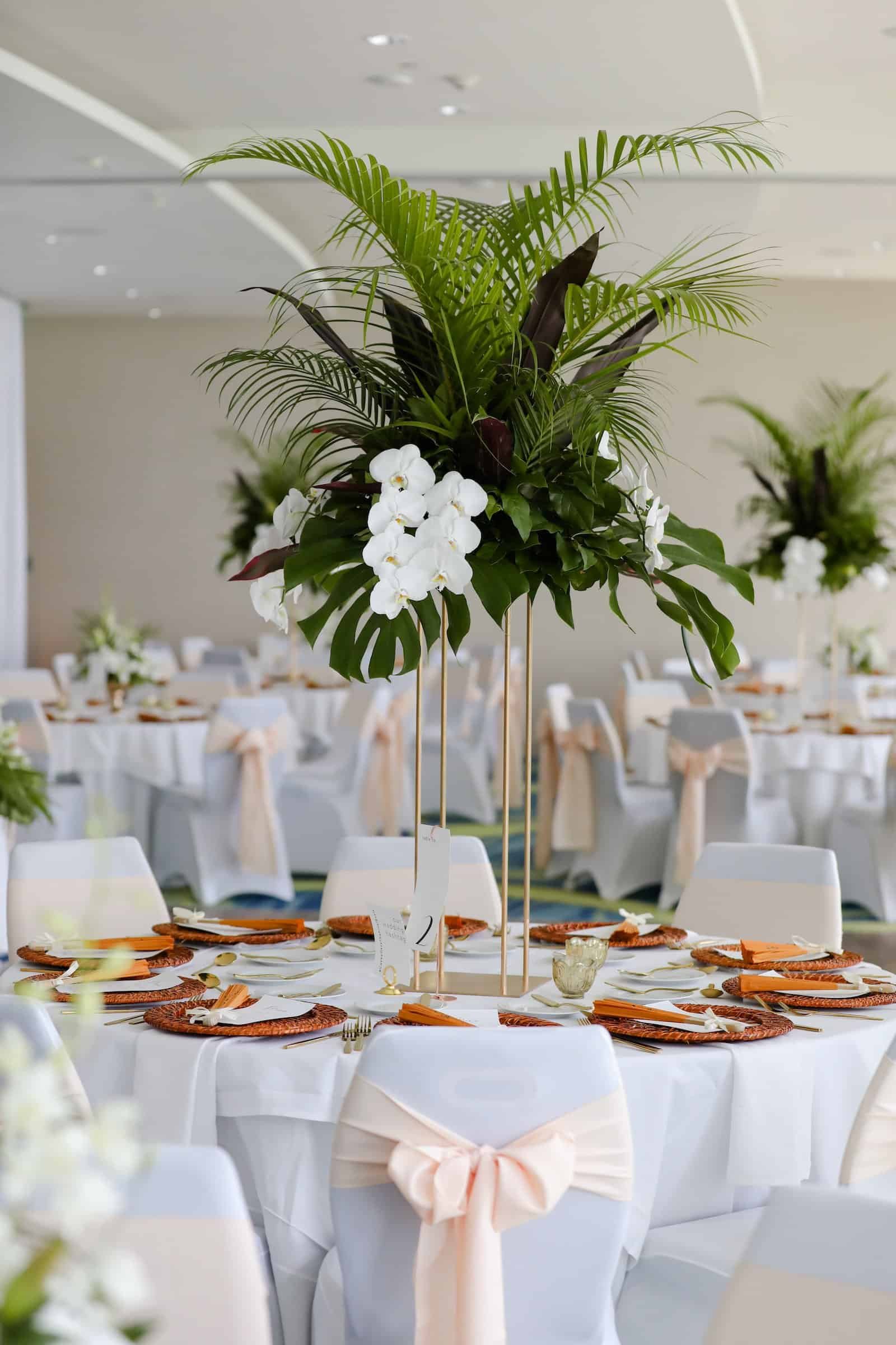 Modern Clearwater Reception Tablescape with Woven Charger Plates, Gold Flatware, and Asian-Inspired Paper Fans